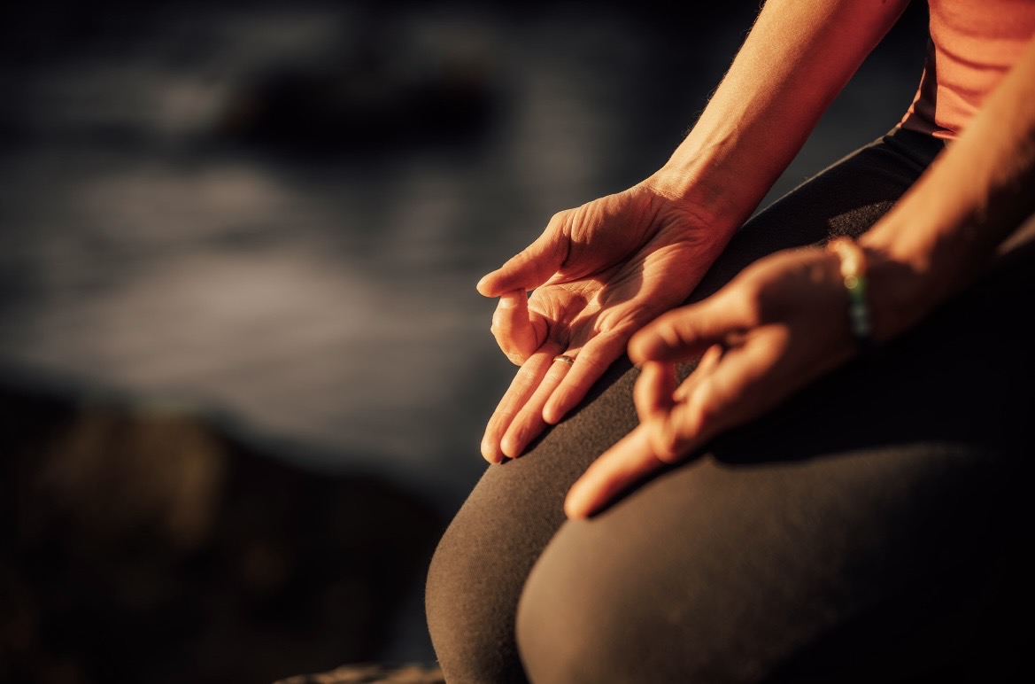 Nahaufnahme zweier Hände in Chin Mudra, auf den Knien abgelegt, im warmen Abendlicht.